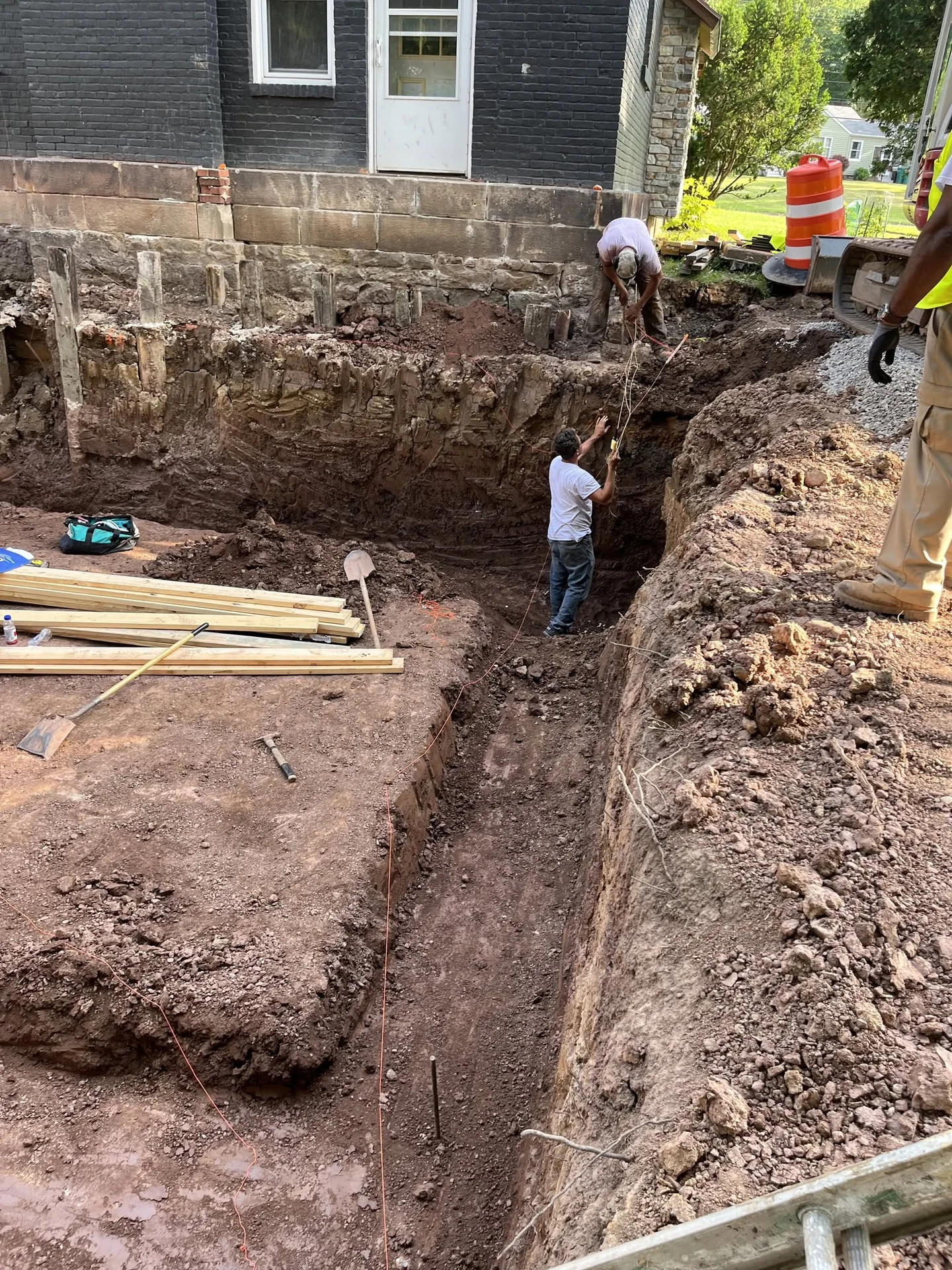 Workers measuring inside a deep residential excavation