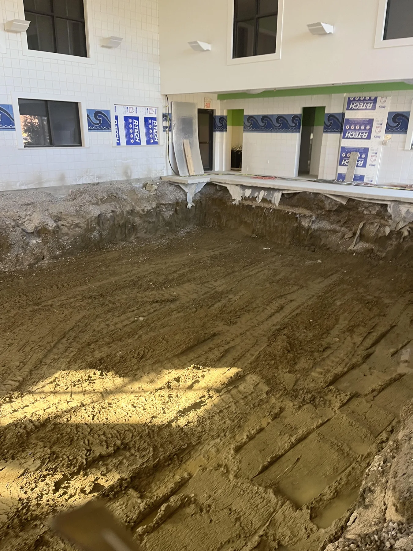Excavator working inside a concrete pool demolition area
